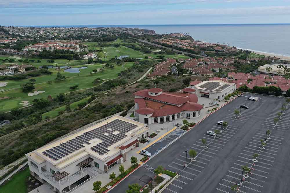 An aerial view of a neighborhood with solar panels installed on rooftops.