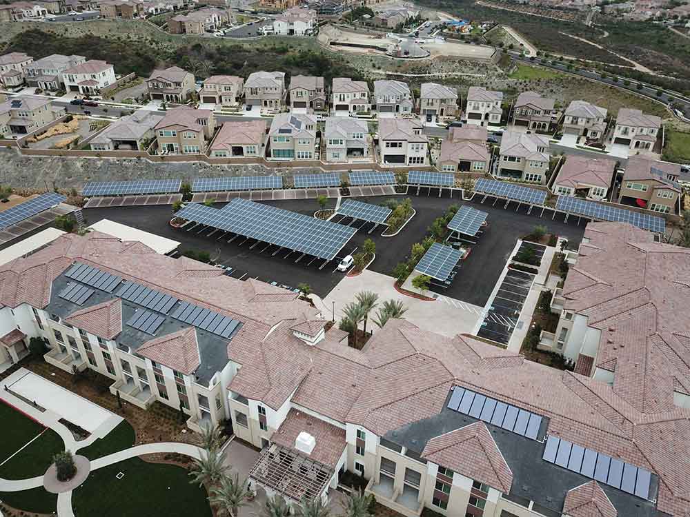 Aerial shot of land with multiple properties using solar energy, featuring solar panels on rooftops.