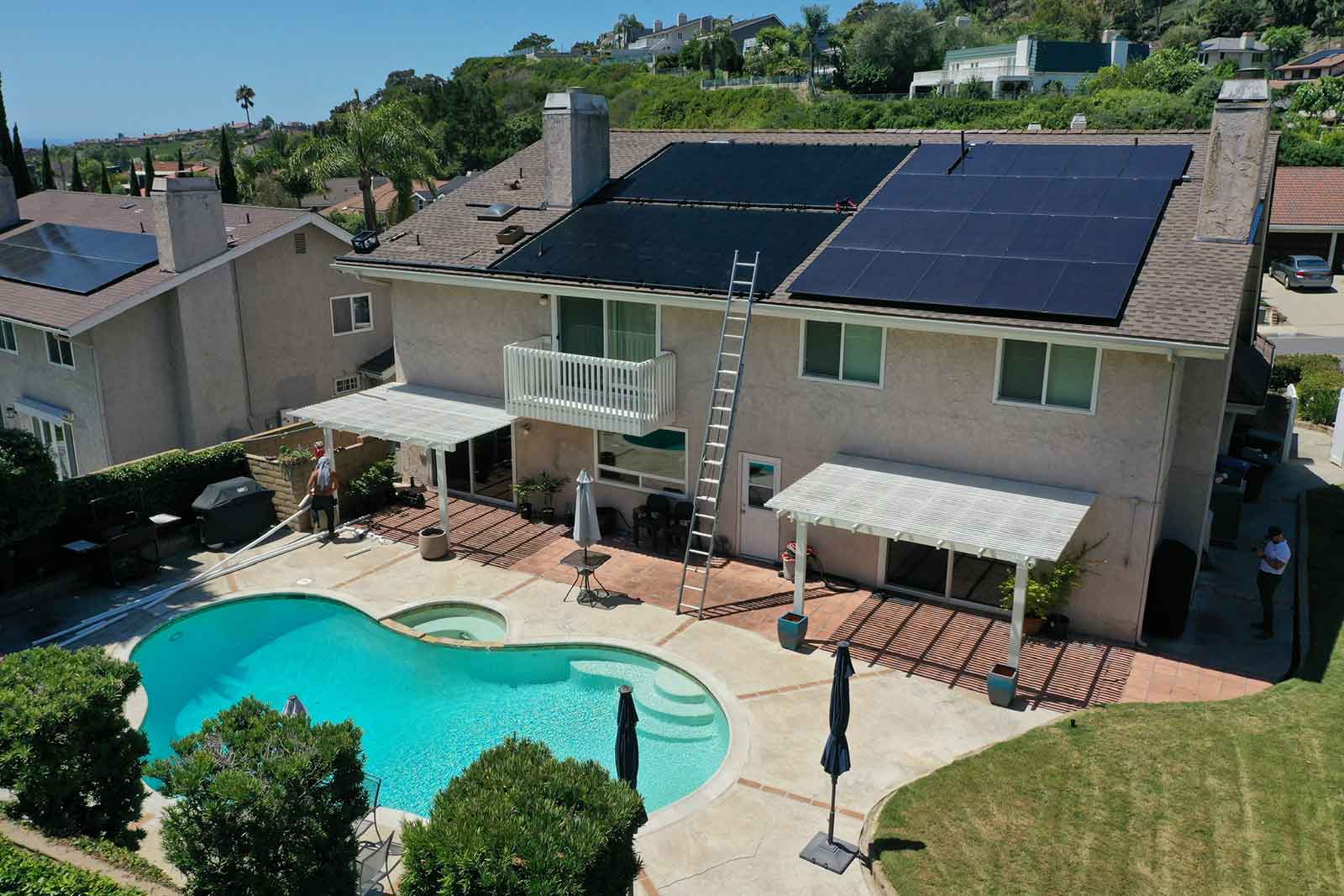 Residential home with rooftop solar panels and a backyard pool