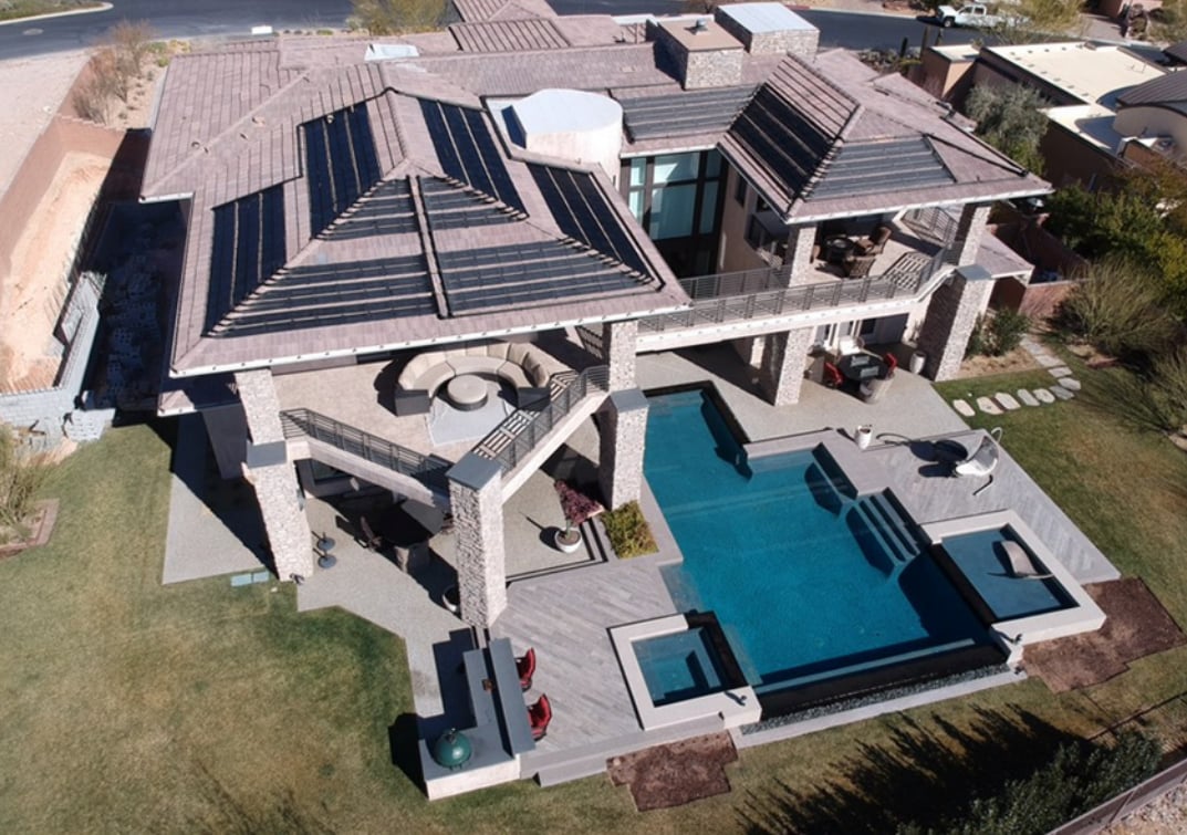 Rooftop solar panels installed by Suntrek Solar on a large modern home with outdoor pool and terrace.
