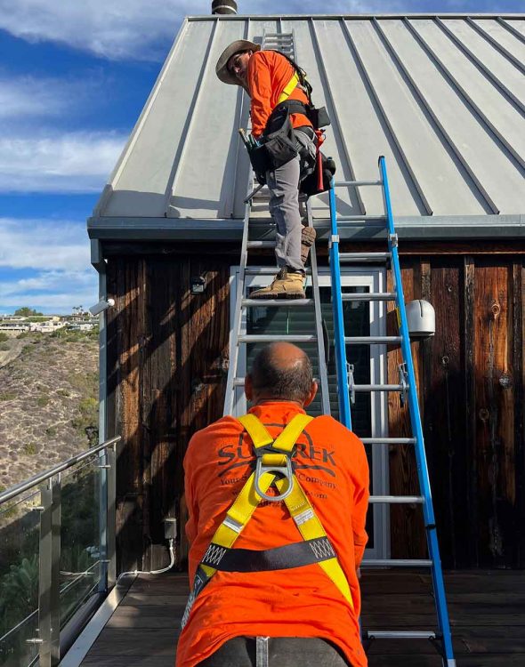 Two technicians working on a rooftop.