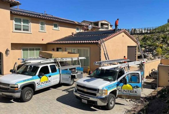 Technicians working on a residential roof, installing solar panels with the tools and equipment in place, during daylight hours.