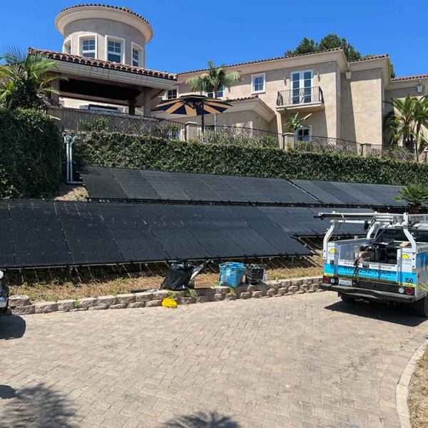 A residential home with a Suntrek pickup truck parked outside and a technician providing solar service