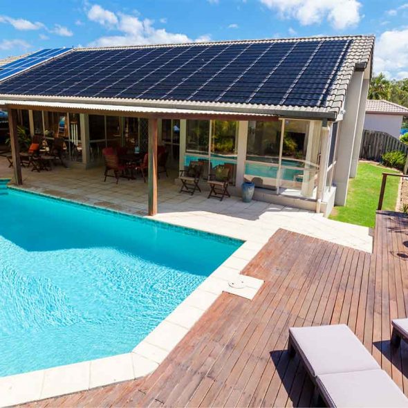 Modern residential house with rooftop solar panels and a backyard swimming pool