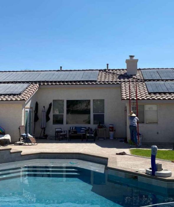A backyard pool at a residential home with solar panels on the roof